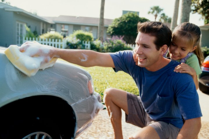 Father with daughter washing insured car.