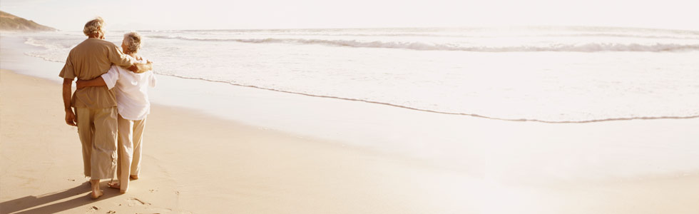 Elderly retired couple walking on the beach.